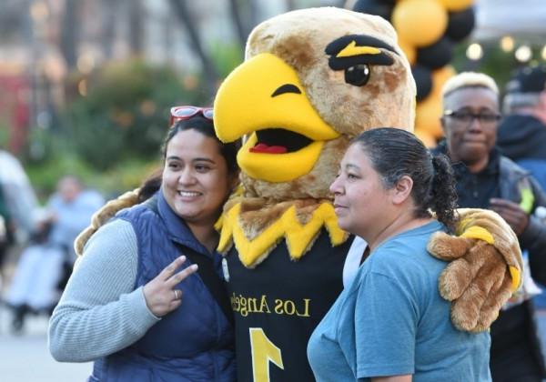 Two people posing with Eddie the Eagle